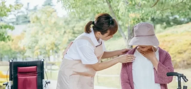 誤嚥してのどを手で押さえる高齢者女性と見守る女性介護士